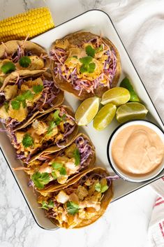 several tacos on a plate with corn and salsa