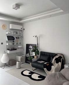 a living room with white walls and black leather furniture in the center, along with an area rug on the floor