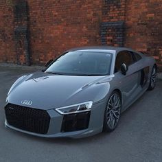 an audi sports car parked in front of a brick wall