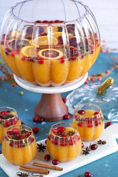 several glasses filled with oranges and cranberries on top of a white plate