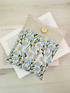 two small blue and yellow flowers are on top of an open book with a button