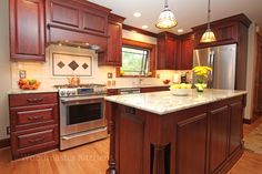 a large kitchen with wooden cabinets and stainless steel appliances, along with an island in the middle