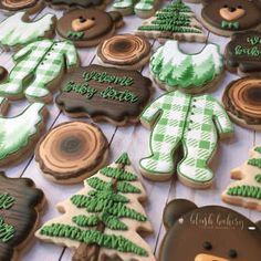 cookies decorated with green and white icing are arranged on a wooden table next to teddy bears