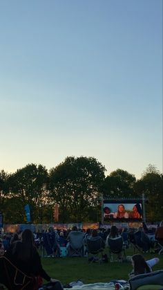 people sitting in lawn chairs watching an outdoor movie on the screen at sunset or dawn