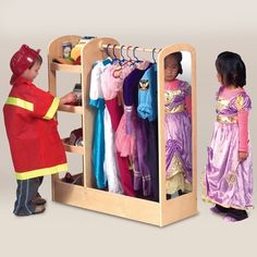 two children looking at clothes on racks in a toy store, one girl is wearing a red coat and the other wears a purple dress