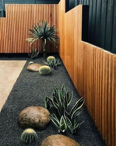 an outdoor area with rocks, plants and wood slats on the side of it