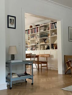 a living room filled with furniture and a book shelf next to a dining room table