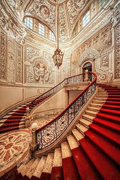 an ornate staircase with red carpet and white walls