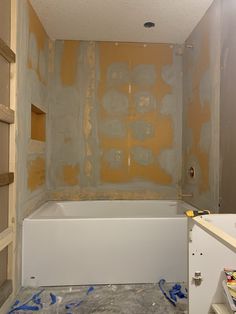 a bath tub sitting in the middle of a room with yellow and white paint on it