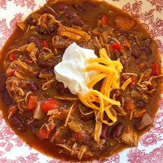 a bowl filled with chili, beans and sour cream on top of a floral table cloth