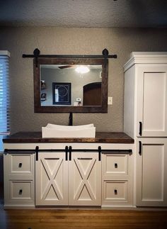 a bathroom with white cabinets and a mirror on the wall above it's sink