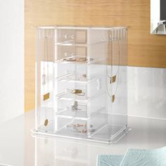 an acrylic display case with jewelry in it on a countertop next to a mirror