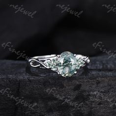 a ring with an oval green stone surrounded by white diamonds on a black background photo