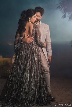 a man and woman standing next to each other in front of a night sky with palm trees