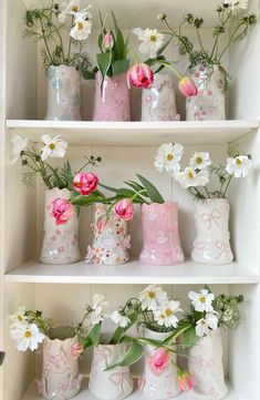 several vases filled with flowers on top of a white book shelf next to each other