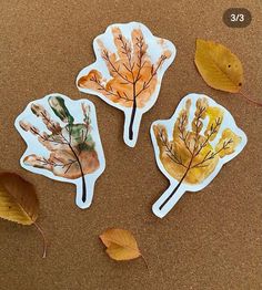 three leaf shaped stickers sitting on top of a table