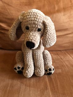 a crocheted dog sitting on top of a brown couch next to a pillow