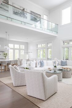 a living room filled with white furniture and lots of windows on top of it's walls