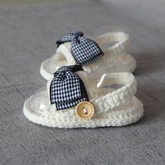 a pair of baby shoes sitting on top of a gray floor next to a button