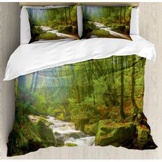 a bed covered in a white comforter next to a forest filled with green trees