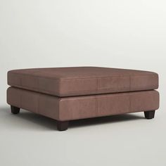 a brown ottoman sitting on top of a white floor