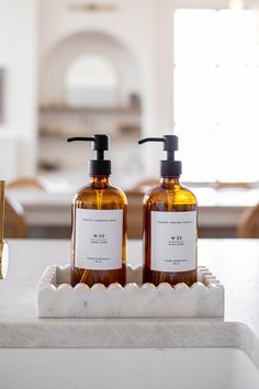 two soap dispensers sitting on top of a marble tray in front of a kitchen counter