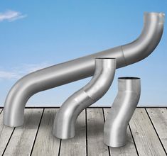 two metal pipes sitting on top of a wooden floor next to a blue and white sky