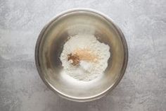 a metal bowl filled with white flour on top of a gray tablecloth covered floor