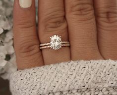 a woman's hand with two rings on it and a flower bouquet in the background