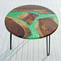 a wooden table with metal legs and green paint on the top, sitting on white sand