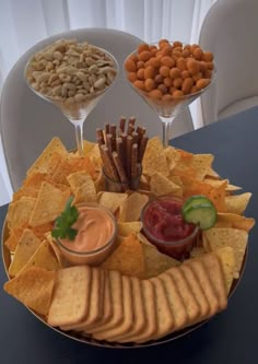 a plate with chips, crackers and dips on it