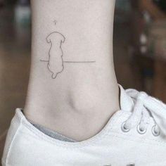 a small tattoo on the ankle of a woman with a dog's head and paw