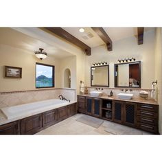 a large bathroom with double sinks and two bathtubs, along with mirrors on the wall