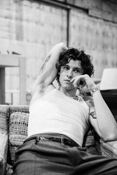 a black and white photo of a man laying on a couch with his hands behind his head