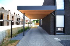 an empty walkway between two buildings in front of a fenced off area with grass