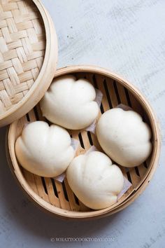 four white buns sitting in a bamboo basket