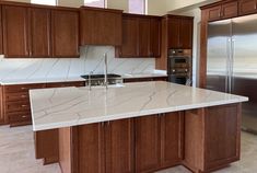 a large kitchen with marble counter tops and wooden cabinets, along with stainless steel appliances