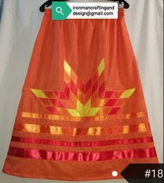 an orange skirt with yellow and red designs on the bottom is hanging from a hanger