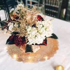 a vase filled with white and red flowers sitting on top of a table next to candles