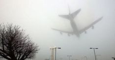 an airplane is flying in the air over some trees and street lights on a foggy day