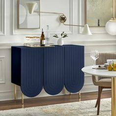 a blue cabinet in a dining room next to a white table with two wine glasses on it