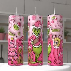 three pink candles decorated with cartoon characters and christmas tree decorations on top of a table