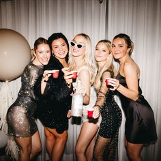 a group of women standing next to each other in front of a wall with balloons