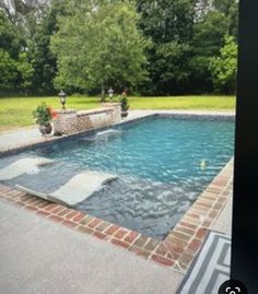 an empty swimming pool in the middle of a yard with brick edging around it