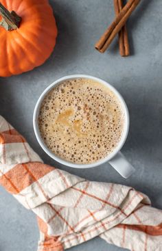 a cup of pumpkin spiced latte next to some cinnamon sticks