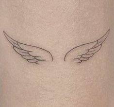 an angel wing tattoo on the side of a woman's thigh, with black ink