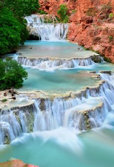 the water is blue and green as it flows over rocks into a river with waterfalls