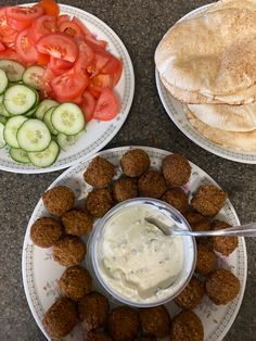 three plates with different foods on them, including pita bread and cucumbers