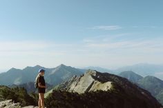 a woman standing on top of a mountain looking at the mountains in front of her