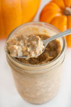 a spoon in a jar filled with oatmeal next to some pumpkins